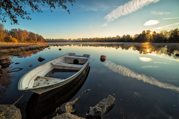 Calm lake with rowboat in autumn scenery