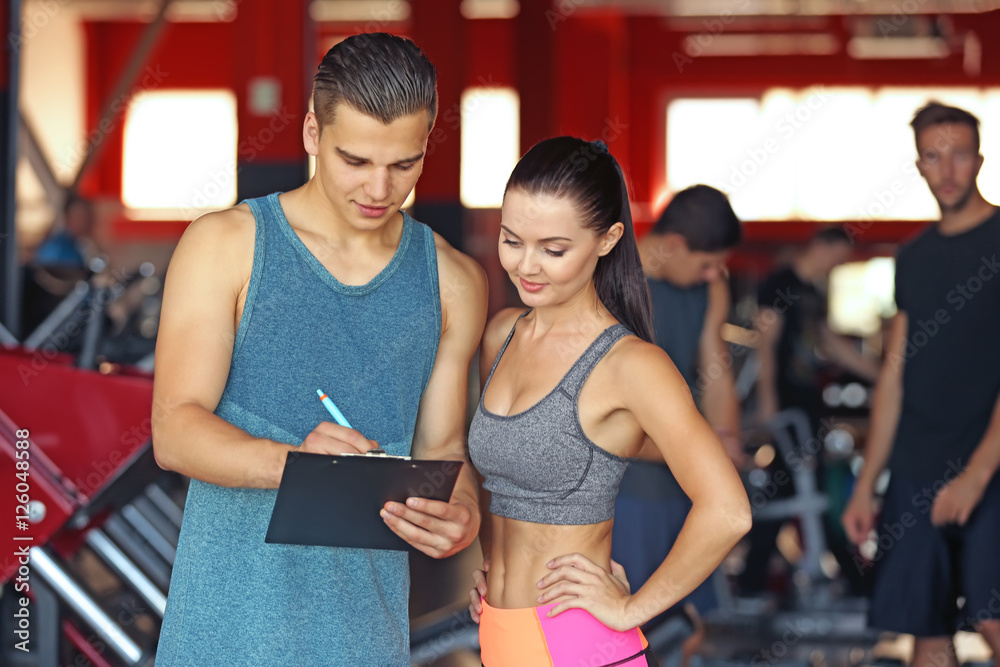 Woman with personal trainer preparing training plan in gym