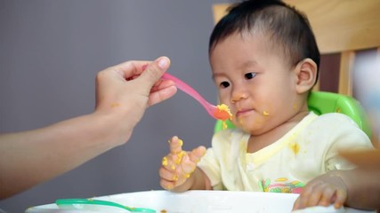 Wall Mural - 9 months old Asian baby try talking while eating food