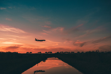 Wall Mural - Passenger Turbofan Airplane is Approaching at the Airport with the Gears down on the top of a Little torrent. Mirror on the Torrent.