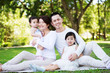 © bearinmind - Young happy Asian family enjoying a sunny day at the park.