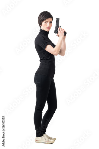 Photo  Side view of armed tough woman holding gun looking at camera