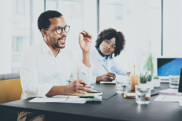 Black african project manager explaning business task in meeting room.Two young entrepreneurs working together in a modern office.Horizontal,blurred background.