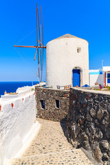 Wall Mural - Typical white windmill on street of Oia village, Santorini island, Greece