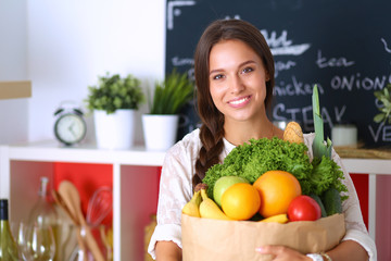 Young woman holding grocery shopping bag with vegetables