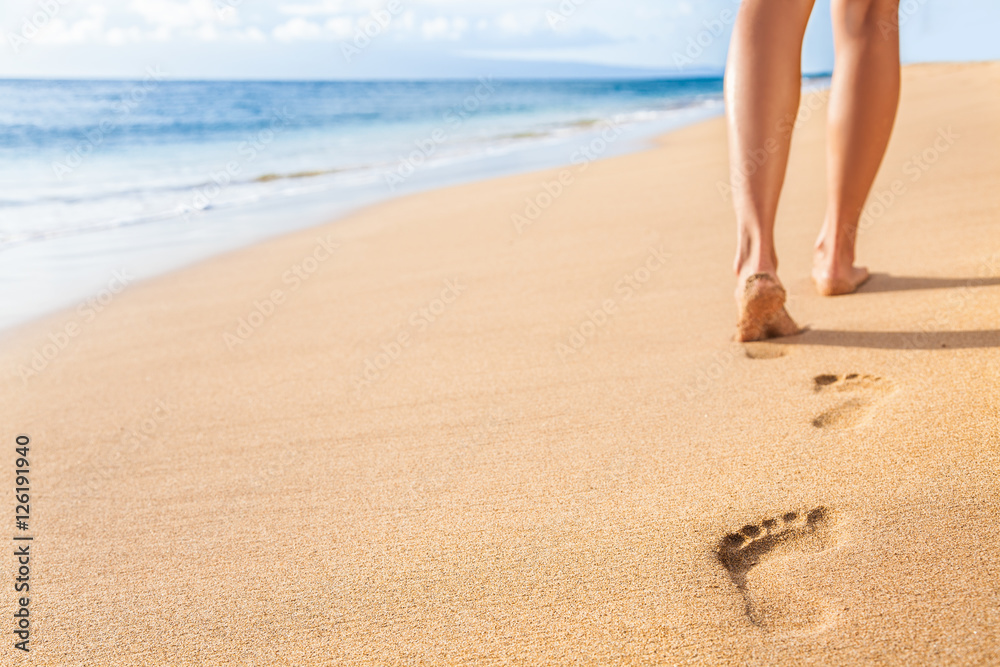Beach travel - woman relaxing walking on sand beach leaving footprints in the sand. Closeup detail of female feet and legs on golden sand on Kaanapali beach, Maui, Hawaii, USA. - obrazy, fototapety, plakaty 