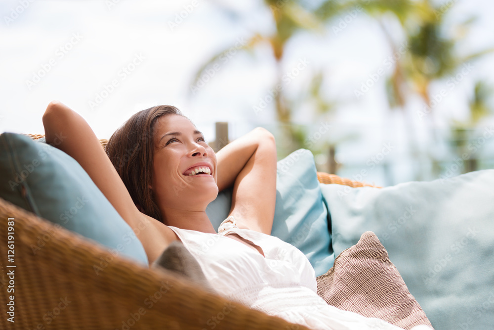Home lifestyle woman relaxing enjoying luxury sofa patio furniture on outdoor patio living room. Happy lady lying down on comfortable pillows daydreaming thinking. Beautiful young Asian chinese girl. - obrazy, fototapety, plakaty 