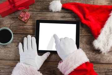 Poster - Santa claus using digital tablet on wooden plank