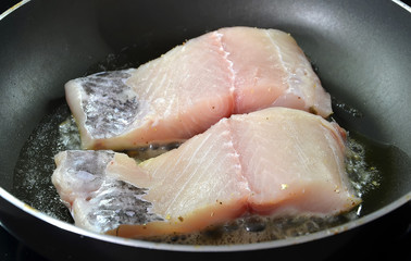 frying raw fish on hot pan cooking photography