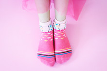 Young Girl And Legs In Pink Socks On Pink Background