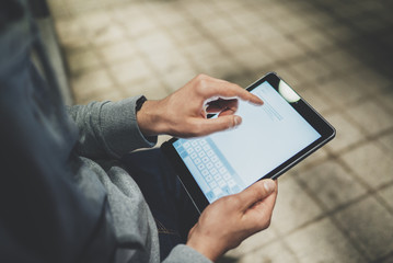 Top view of male hands holding and using modern digital tablet device at night, hipster guy typing an sms message via portable tablet outdoor, social networking concept