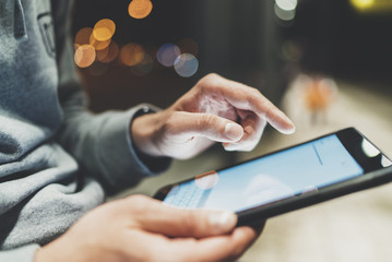 Closeup of male hands using modern digital tablet at night outdoor, technology and social networking concept, hipster guy typing on touch screen of portable computer, bokeh light in blurred background