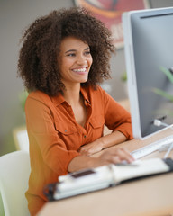 Wall Mural - Cheerful businesswoman working on desktop computer