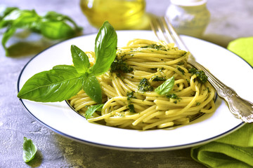 Spaghetti with basil pesto on a white plate.