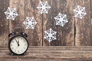 Clock with five mintes to twelve o`clock on old wooden background