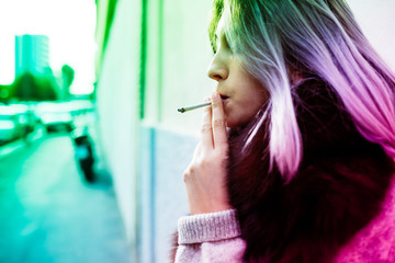 Young beautiful caucasian purple grey hair woman outdoor in the city smoking a cigarette - bad habit, addiction concept