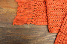Orange Knitted Scarf Close-up  On The Wooden Background