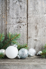 Silver and white christmas ornaments, xmas tree on rustic wood background. Merry christmas card. Winter holiday theme. Happy New Year. Space for text.