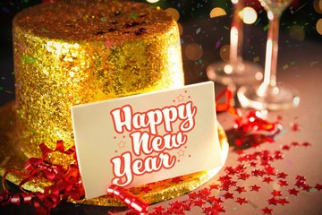 Digital composite of Happy new year card leaning on gold party hat