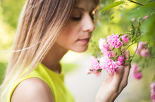 Beautiful Blond Woman Smelling Pink Rose Flowers. Sunny Summer.