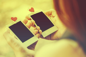 Woman looking love photo instant on hand and nostalgia lovers. 2 Blank instant photo and red clip paper heart. relationship concept.Vintage or retro tone.