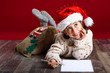 © javiindy - Adorable little girl wearing santa hat writing Santa letter