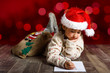 © javiindy - Adorable little girl wearing santa hat writing Santa letter