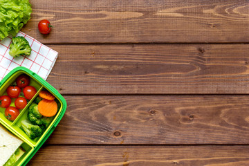 green lunch box for kid on wooden background top view