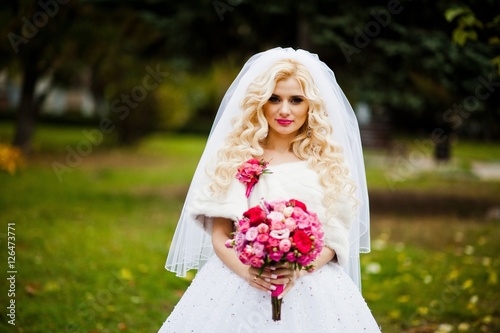 Fotografie, Obraz Portrait of charming blonde bride in a fur coat with bouquet