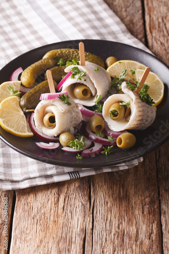 Fotografie, Obraz rolls of marinated herring with olives, onions, pickles and lemon close-up on a plate