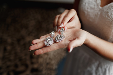 Wedding earrings on a bridal hand, bride's morning and jewelry accessories and decoration concept