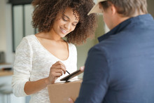 Mixed Race Woman Receiving Package From Delivery Man