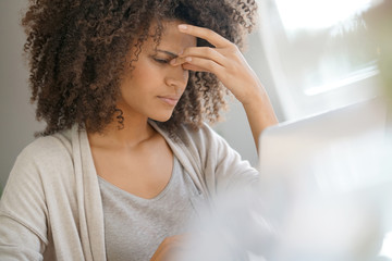 Wall Mural - Mixed race woman having a headache working on laptop