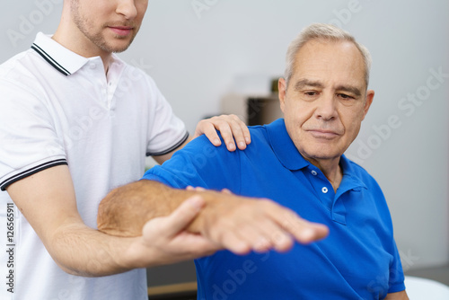 Fotomural orthopäde untersucht die schulter eines älteren patienten