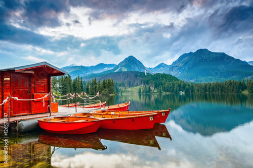 Boats stand near wooden bridge and a hut on a mountain lake.