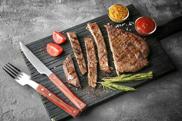 Wall Mural - Delicious sliced steak with spices on board and grey table