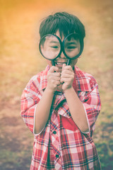 Wall Mural - Asian child with magnifying glass at park on vacation. Education