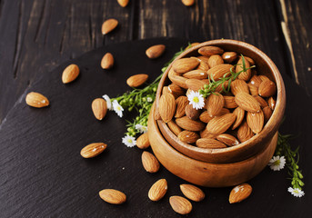 raw almonds on wooden bowl, selective focus, space for text