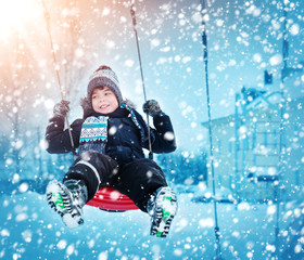 Wall Mural - Boy in knitted hat, gloves and scarf outdoors at snowfall. Child in winter clothes