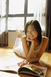 © Alexander - Young woman lying on floor with magazine, looking at camera