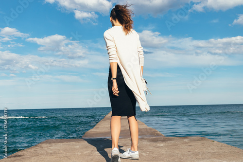 Fotografía Slim brunette woman in a skirt, cardigan and sneakers walking on