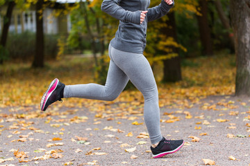 close up of young woman running in autumn park