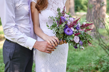 Wall Mural - groom embracing bride with beautiful wedding bouquet