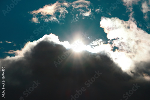 Fotografie, Obraz Die Sonne scheint durch eine dicke Regenwolke über den geteilten Himmel