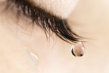 Sad Woman Concept - Closed Eyelid Closeup With A Teardrop On Eyelashes.  A Tear On Eyelashes Macro Close-up. A Tear Runs Down His Cheek. Tinted Beige.