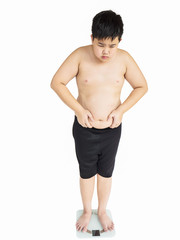 Soft focus of fat boy disappoint his fatness while standing on on weighing machine over white background