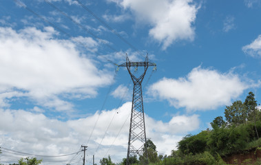 Electricity pylon silhouetted against blue sky wih cloud backgro