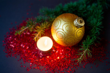 Christmas composition - golden ball, spruce branch and a burning candle.