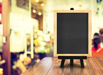 Poster - Blackboard with easel on wood table at blurred coffee shop backg