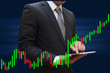 © nanantachoke - Businessman using tablet smartphone under Candlestick Chart, inv